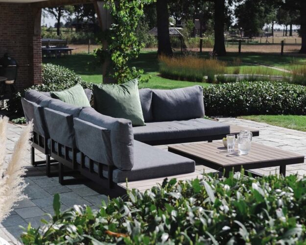 loungeset van polywood met kussens in een tuin gezet